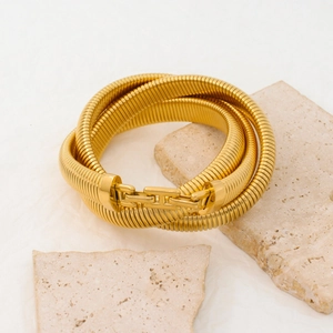 Detailed close-up of a gold multi-layer snake bone bracelet on a stone pedestal