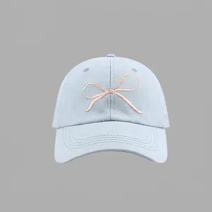 Detailed pink ribbon bow embroidery on a light blue cotton baseball cap with curved brim