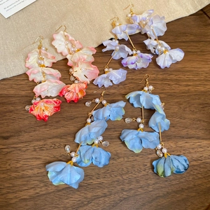 Gros plan sur des boucles d'oreilles fleurs en tissu avec perles en trois tons pastel
