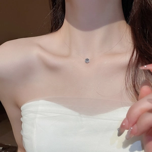 Dettaglio di una collana con ciondolo in zircone e filo di nylon invisibile indossata
