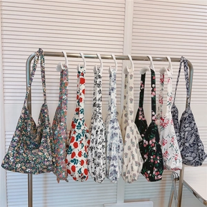Collection of floral cotton tote bags with various vintage prints hanging on a metal rack