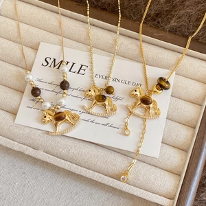 Detail view of gold rocking horse pendants with tiger eye stone and crystal inlay