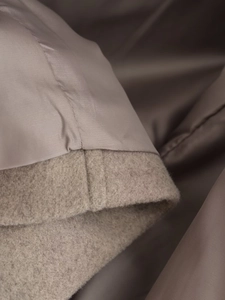 Détail macro du tissu en laine et des coutures de la doublure soyeuse sur un manteau beige