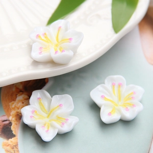 Macro shot of white resin cherry blossoms with yellow centers for DIY jewelry crafting