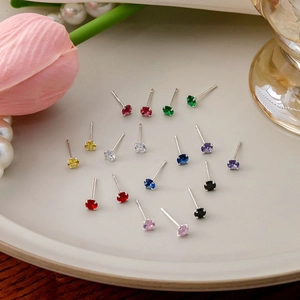 Minimalist tiny zircon stud earrings in various colors displayed on a ceramic tray
