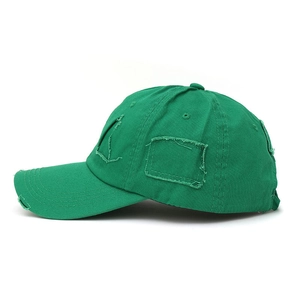 Close-up of distressed dark green baseball cap featuring ripped edges and vintage patches