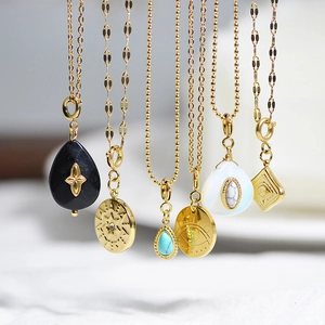 Detail view of gold stainless steel pendants with natural stones and bohemian designs