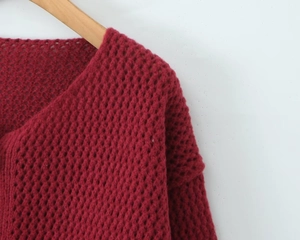 Dettaglio dello scollo del cardigan rosso in maglia grossa con trama traforata