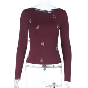 Close-up of burgundy long sleeve top with sparkling crystal rhinestone embellishments