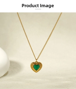 Macro shot of vintage gold heart pendant with green gemstone and wavy metal textures