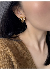 Close-up of 18K gold plated flower stud earring with pearl inlay on model ear