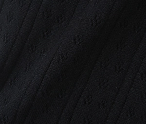 Gros plan sur la maille côtelée noire révélant un motif floral et une texture de tissage