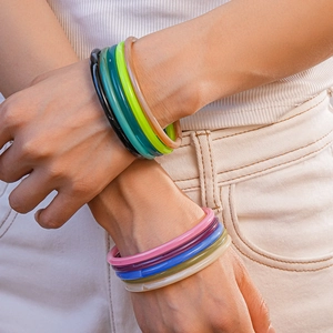 Close-up of colorful translucent acrylic bangles worn by a model in vibrant resin colors