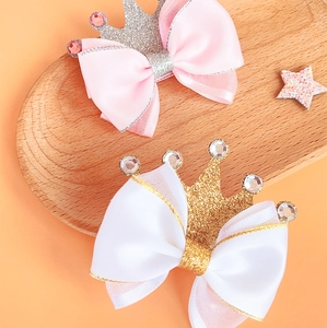 Detail of pink and white satin bow hair clips with glitter crowns and rhinestones