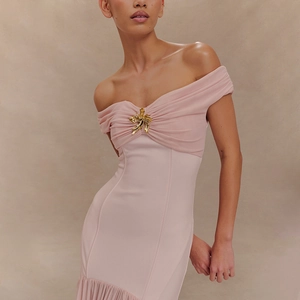 Detailaufnahme von rosa trägerlosem Kleid mit eleganter goldener Blumenbrosche und Falten