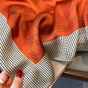Detailed view of polka dot silk scarf featuring smooth satin texture and elegant curves