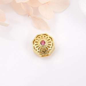 Macro detail of 18k gold plated hexagonal hollow bead with pink gemstone for DIY jewelry