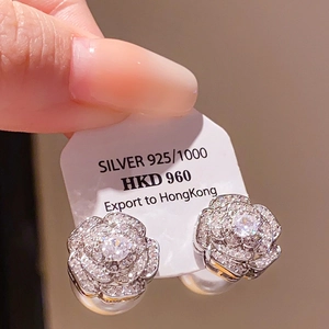 Close-up of 925 sterling silver camellia flower earrings with sparkling pavé cubic zirconia