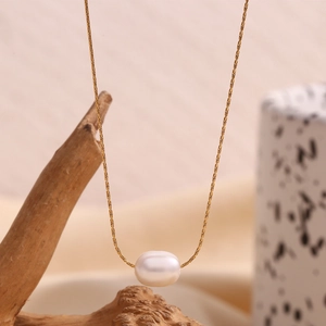 Close-up of 18K gold plated chain with an oval white pearl pendant on rustic wood