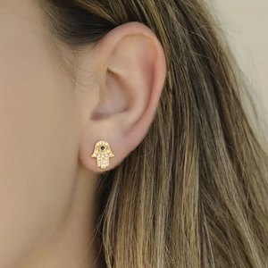 Gold Hamsa hand earrings with blue evil eye and sparkling cubic zirconia on model