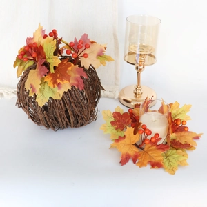 Detail of harvest candle ring with autumn maple leaves, berries and a rattan sphere ball