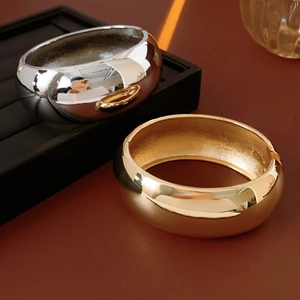 Macro detail of wide metal bangles in gold and silver finish with high mirror polish