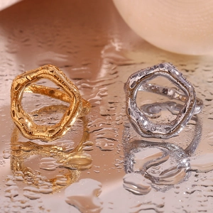 Close-up of irregular lava-style rings in gold and silver finish on a water droplet surface