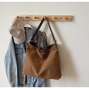 Detailed view of a brown large-capacity canvas tote bag hanging in a cozy interior setting