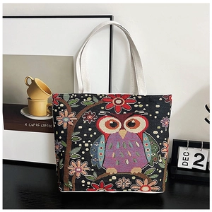 Close-up of ethnic canvas tote bag featuring a colorful owl embroidery and woven texture