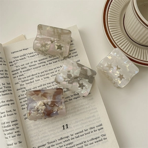 Iridescent square star-patterned hair claw clips on an open book background