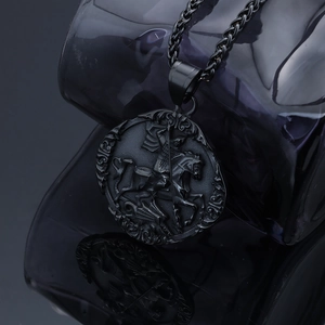 Macro shot of black St. George and the Dragon relief on a round stainless steel pendant