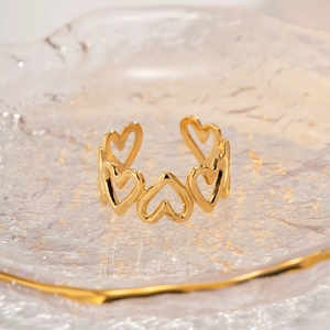 Detail of hollow heart-shaped ring with polished gold finish on a glass tray