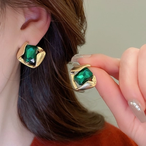 Detailed close-up of emerald green geometric square earrings with gold vintage frames