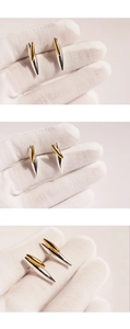 Detailed close-up of two-tone gold and silver rivet stud earrings in conical design