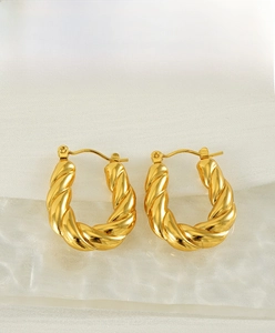 Detail of chunky gold twisted hoop earrings with textured finish and secure snap closure