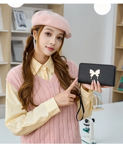 Close-up of black long leather wallet with gold butterfly clasp held by a model