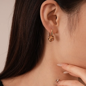 Close-up of model wearing geometric gold sphere earrings with amber-colored crystals