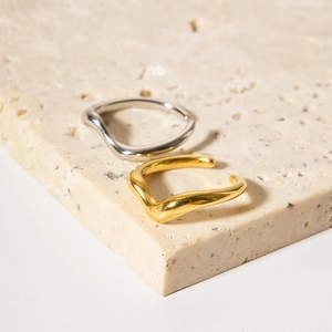Detail showing irregular wavy gold and silver stainless steel rings on stone base