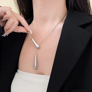 Gros plan d'un collier avec pendentif goutte d'argent sur un mannequin en blazer noir