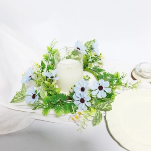 Floral wreath candle holder with light blue daisies and green leaves on white fabric