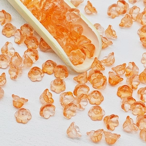 Macro detail of amber orange lily of the valley glass beads on a bamboo spoon for DIY crafts