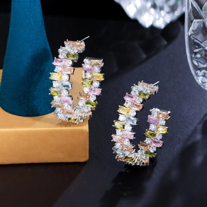 Detailed view of C-shaped earrings with colorful square-cut zirconia in claw setting