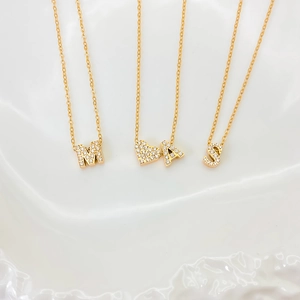 Detail of gold-plated letter M A S pendants with sparkling cubic zirconia on a chain