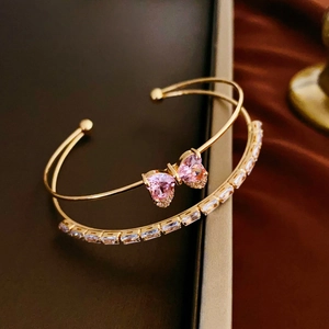 Double-layered gold open bracelet with pink heart zirconia bow and crystal baguette stones