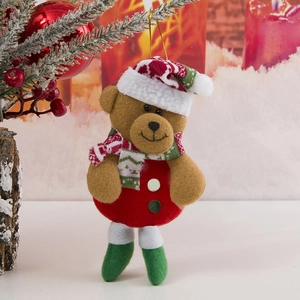 Detalle de un osito navideño con gorro nórdico colgado de una rama de pino nevada