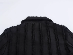 Close-up of black blazer coat collar and shoulders with distinct frayed edge detailing
