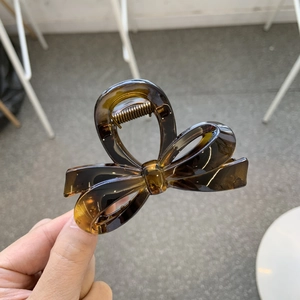 Detail showing amber resin bow hair claw clip with a transparent finish and metal spring