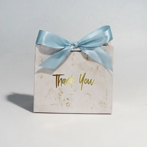 Detail of marble pattern gift box with golden Thank You text and light blue ribbon bow