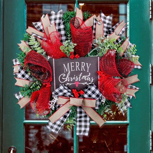 Christmas wreath with mesh ribbons and red berries on a green wooden door