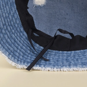 Macro detail of denim sun hat showing frayed edges and adjustable inner windproof strap